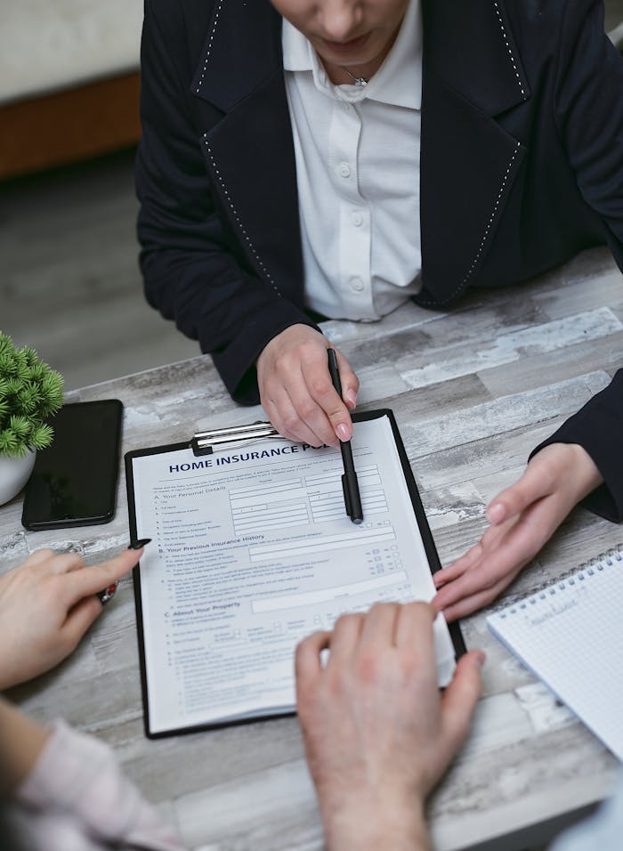 our-services-2 An agent and clients discussing paperwork for home insurance at a meeting table.