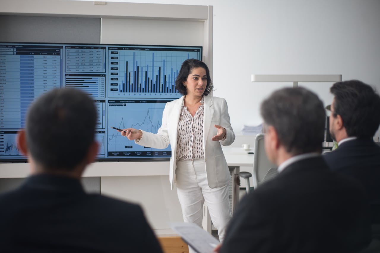 hero-img-02 Professional woman presenting stock market data in a modern office setting.